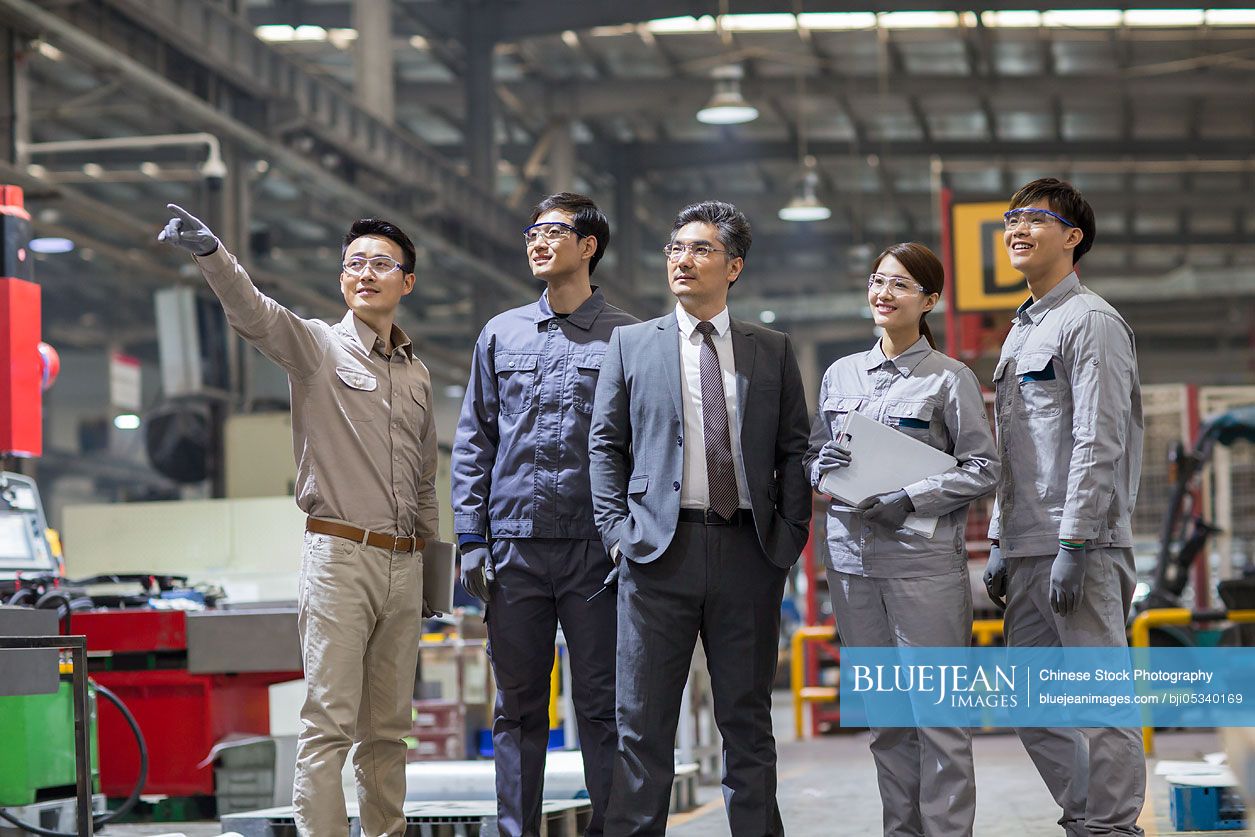 Confident Chinese businessman and engineering team in the factory