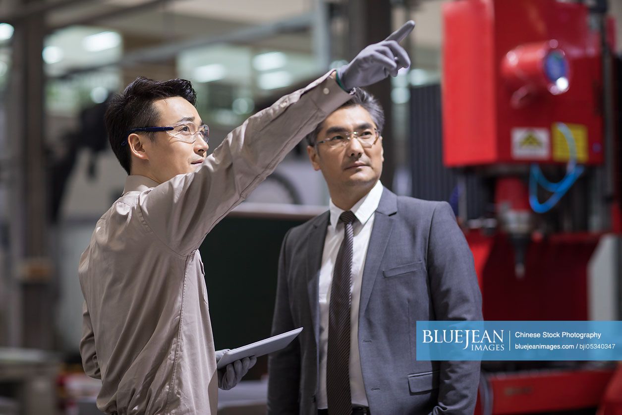Chinese businessman and engineer talking in the factory