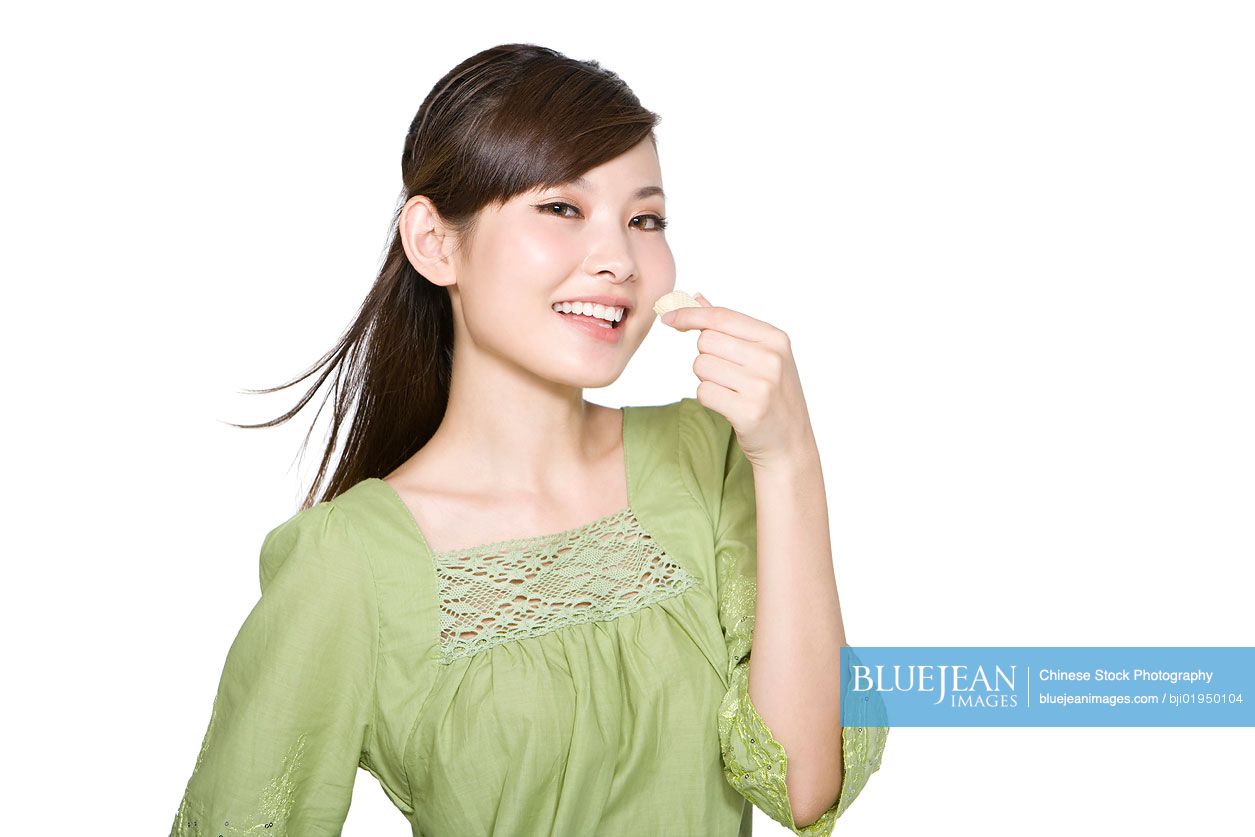 Portrait of young Chinese woman eating wafer cookie