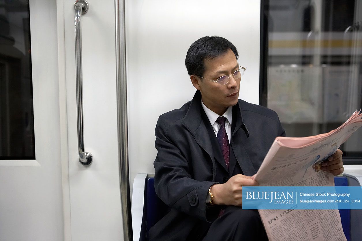 Chinese man reading newspaper on train