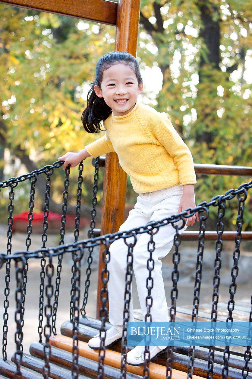 Chinese girl playing on playground toy bridge