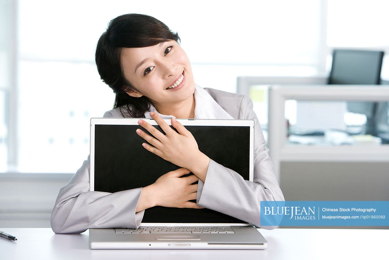 Chinese office worker hugging her computer