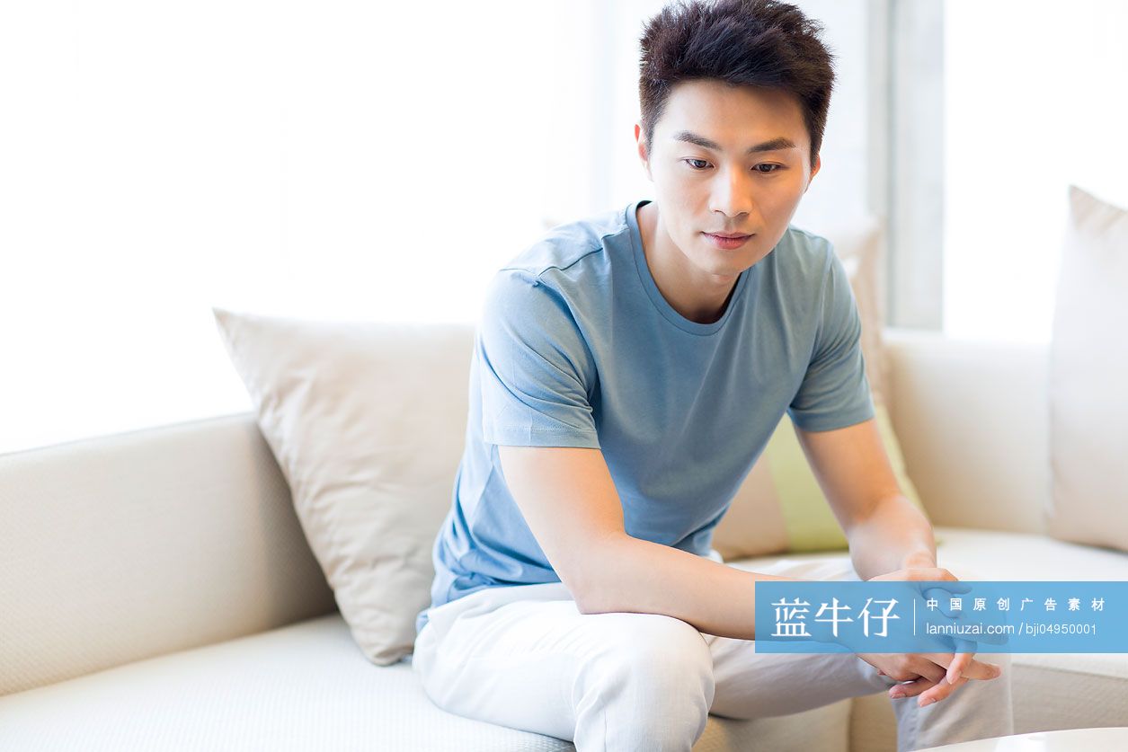 年轻男子坐在沙发上思考