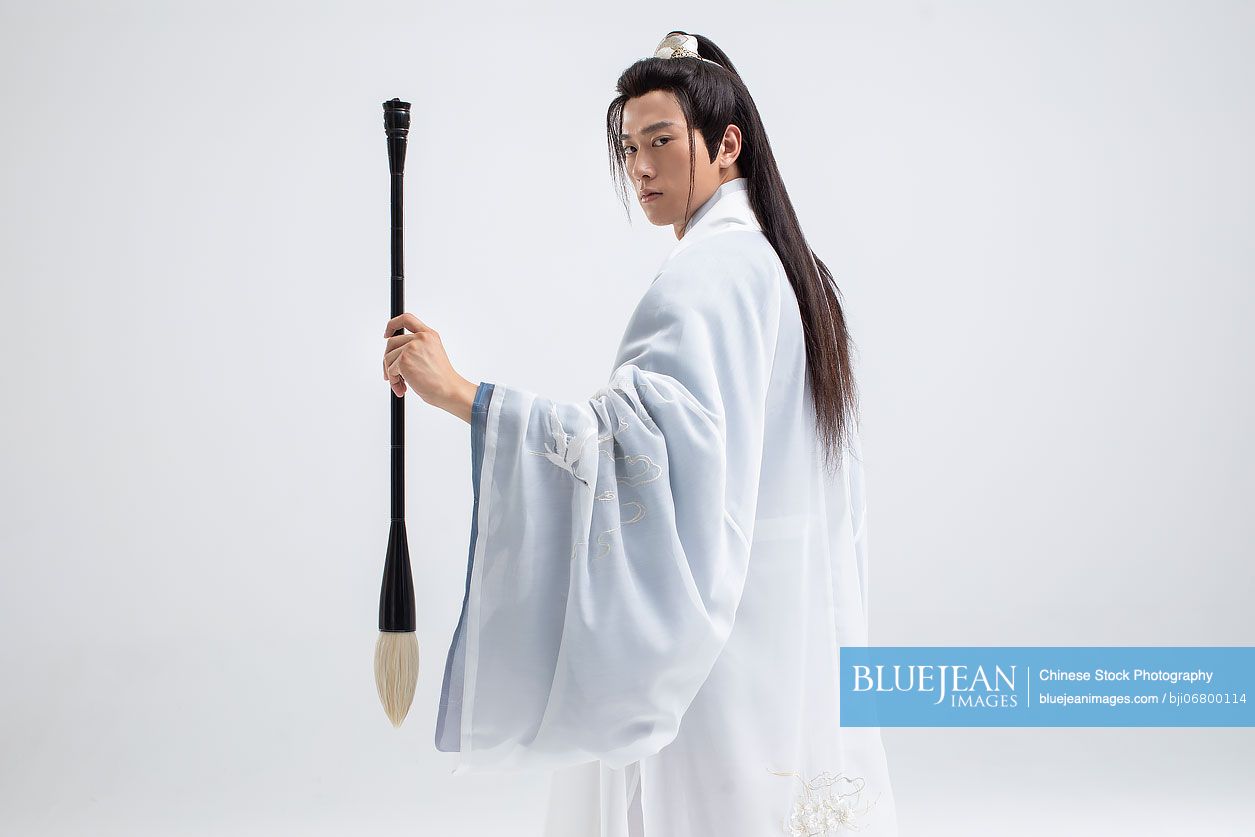 Young Chinese man in ancient costume holding an ink brush