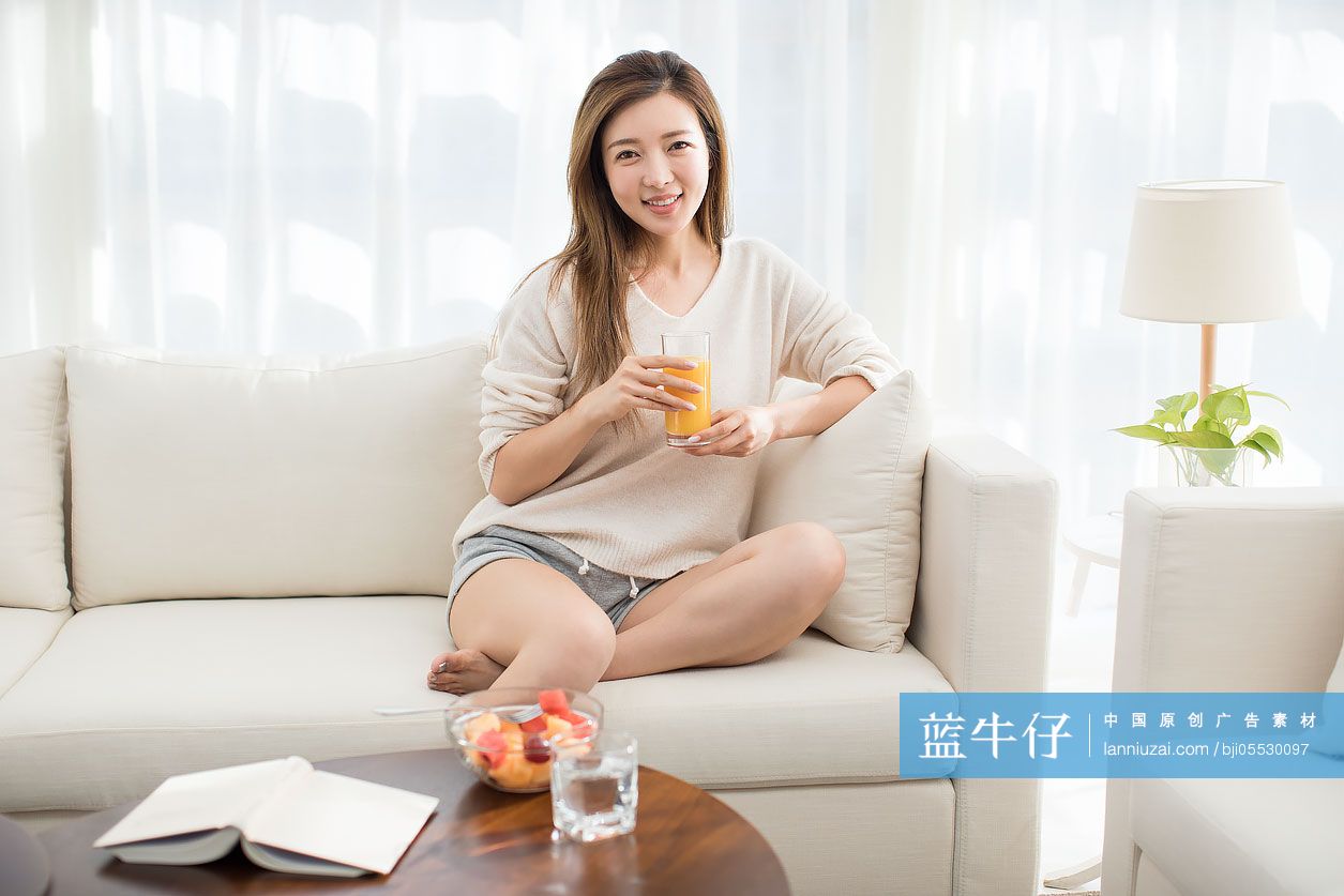 年轻女子在沙发上喝果汁