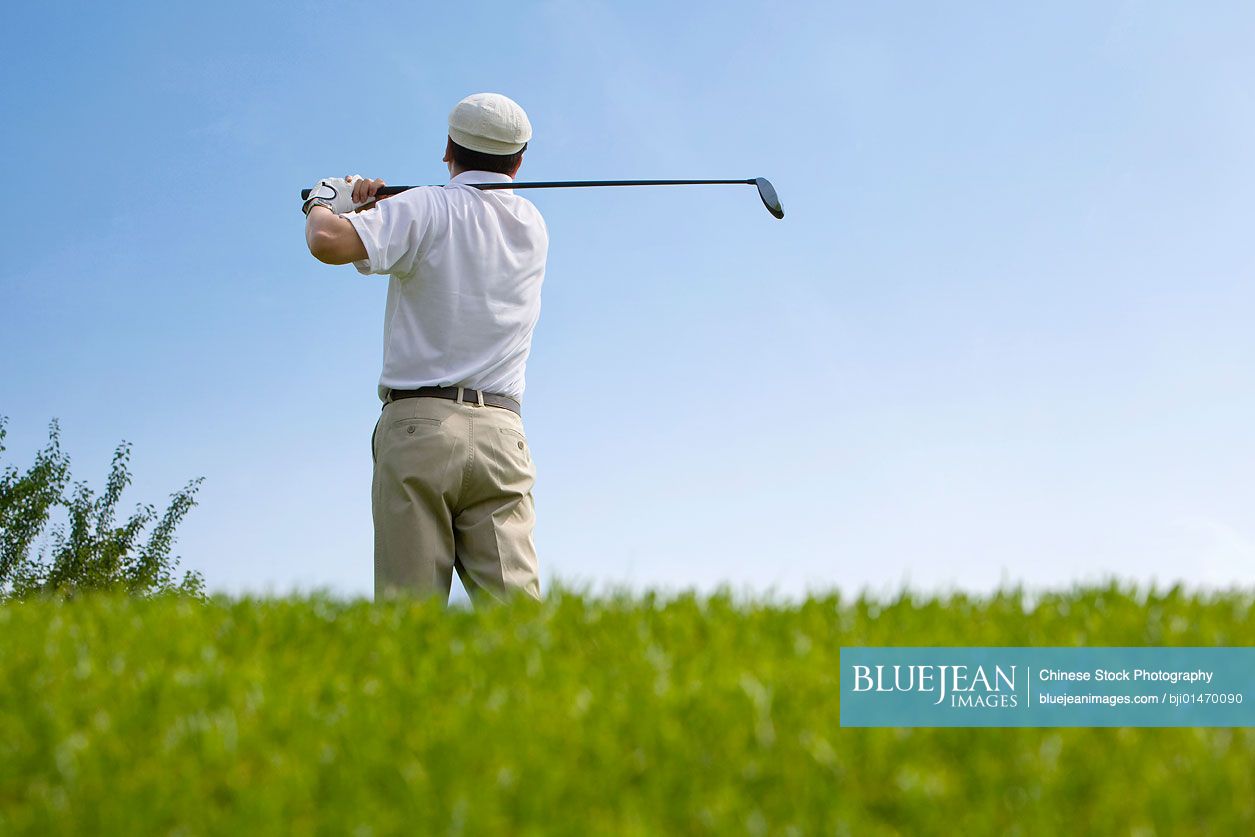 Male Chinese golfer swinging club