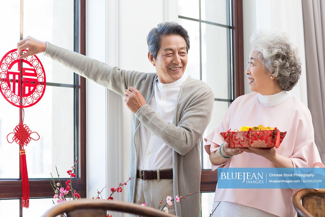 Senior couple decorating their house for Chinese New Year