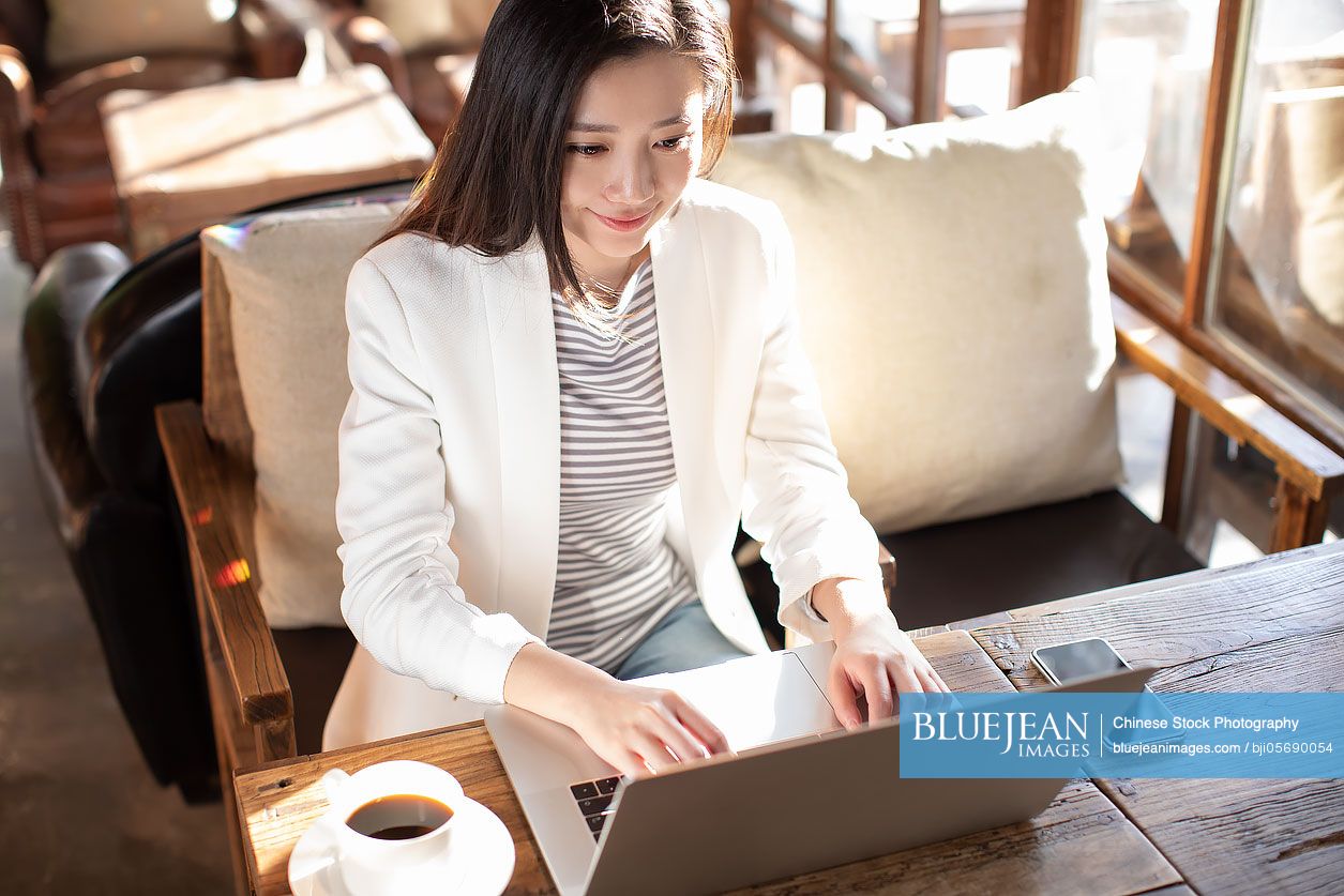 Young Chinese businesswoman using laptop in coffee shop
