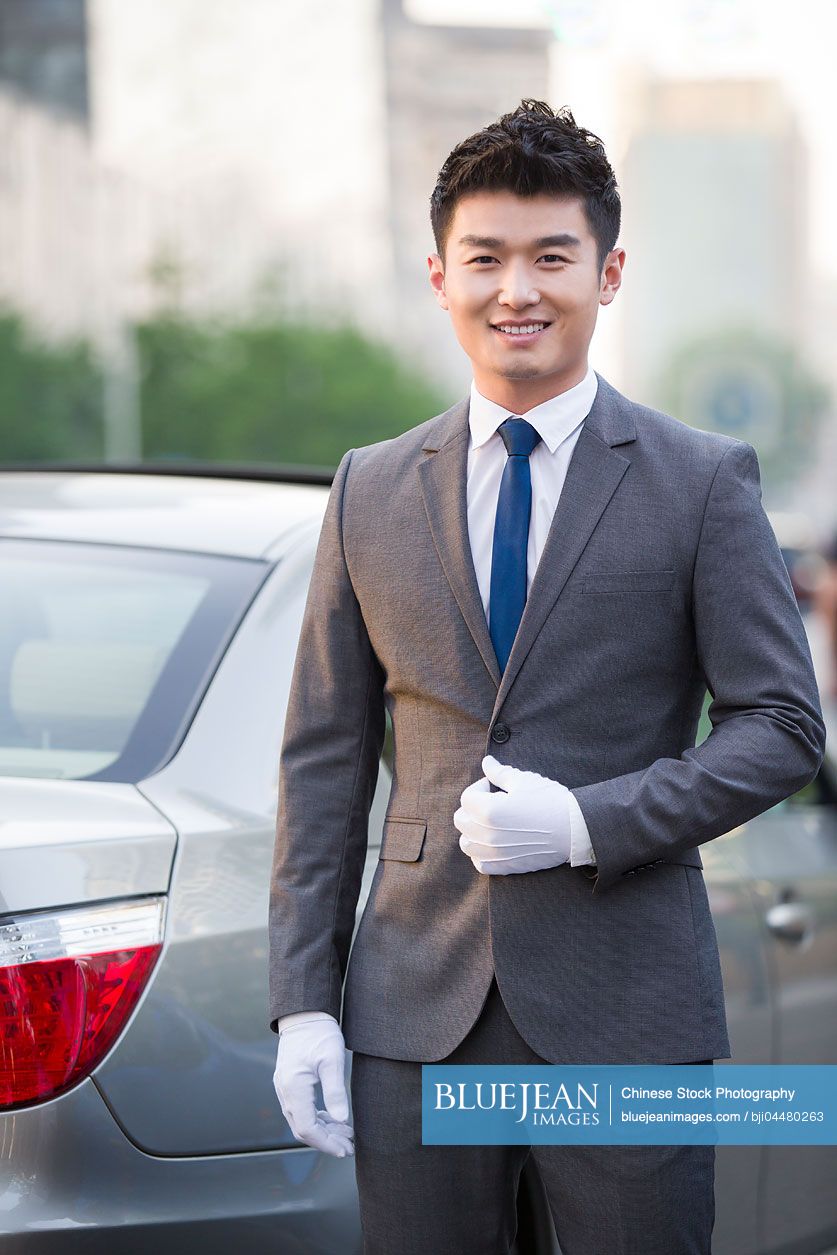 Portrait of Chinese chauffeur standing next to the car