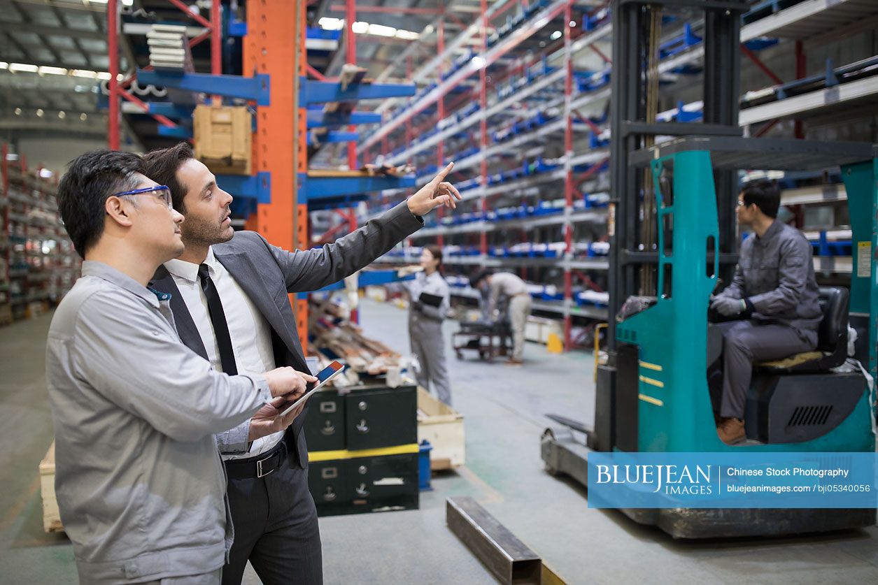 Businessman and engineer talking in the factory