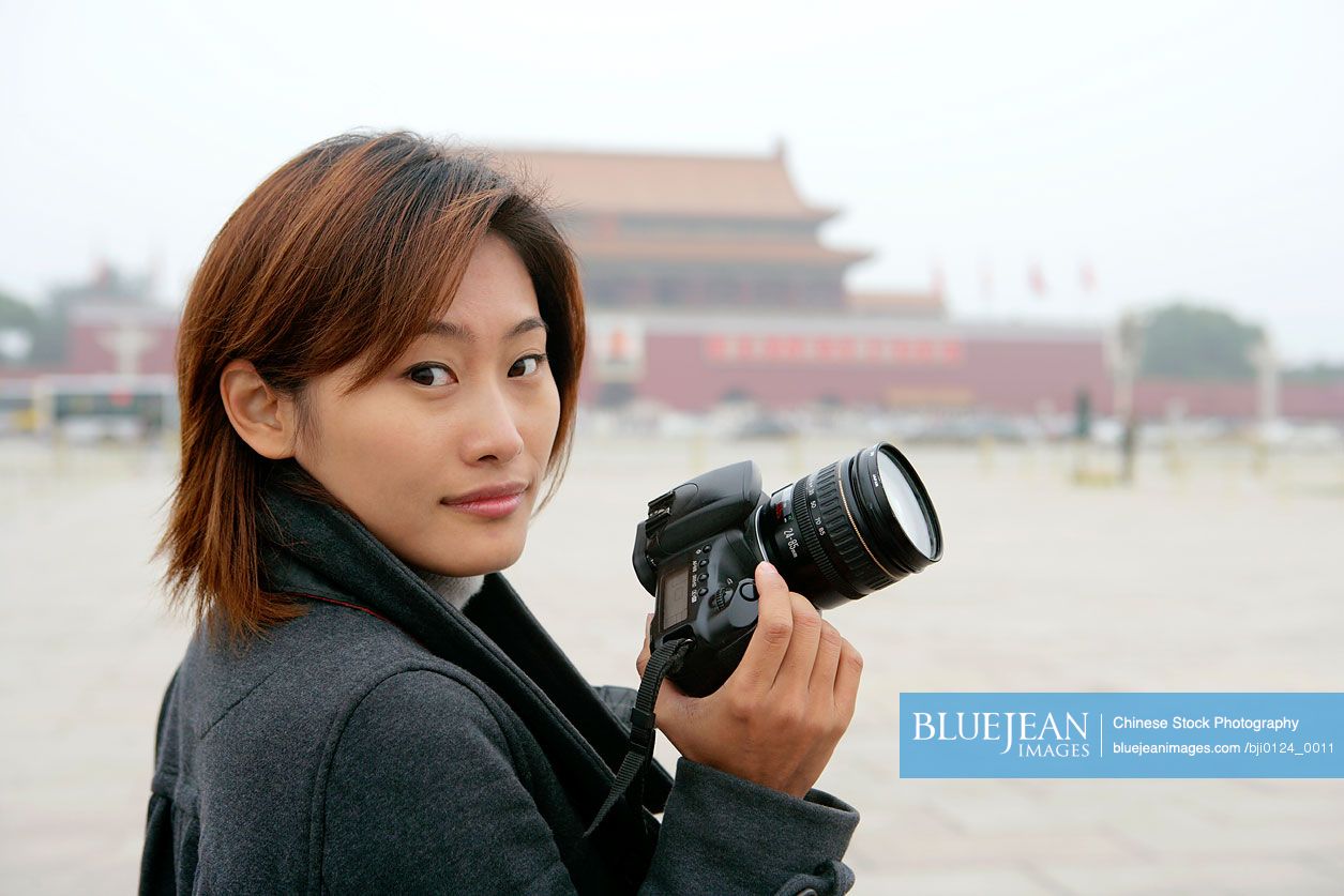 Young Chinese woman holding camera, Tiananmen Square, Beijing, China