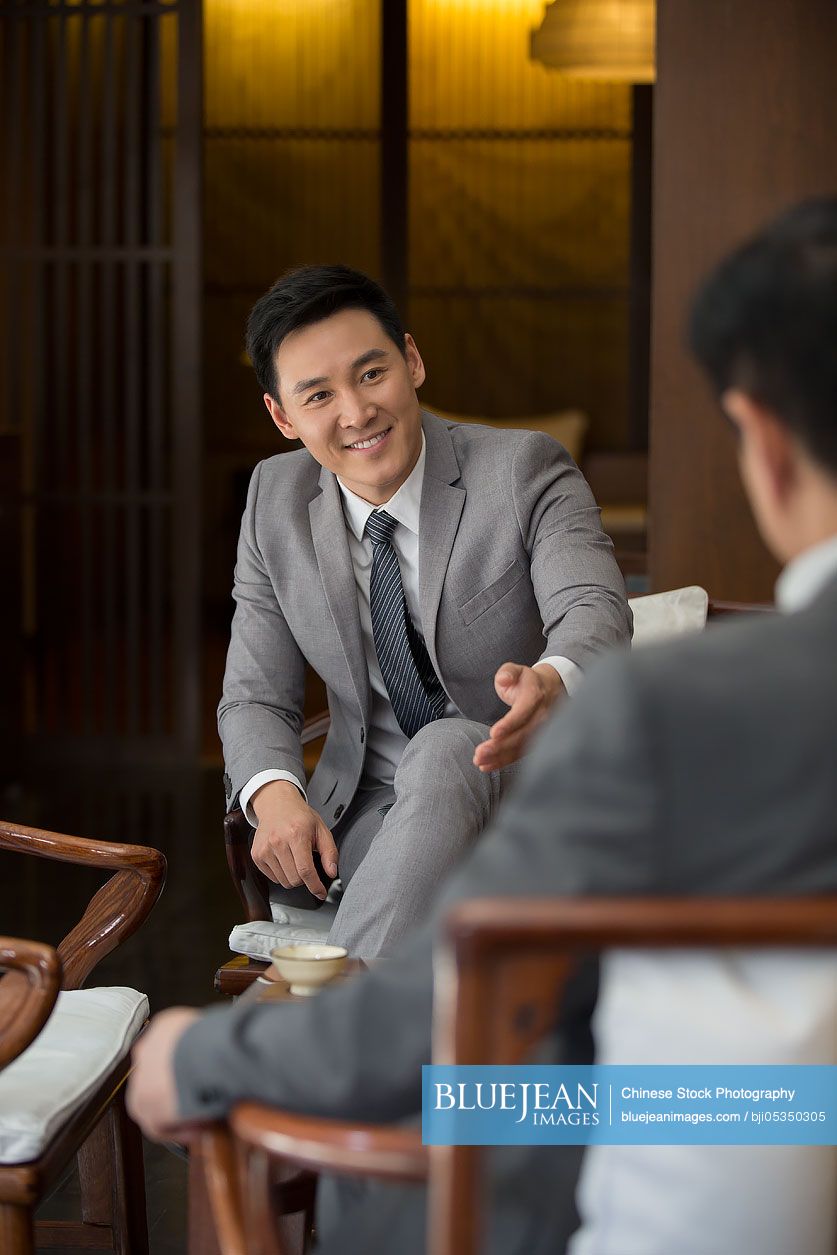 Cheerful Chinese businessmen talking in tea room