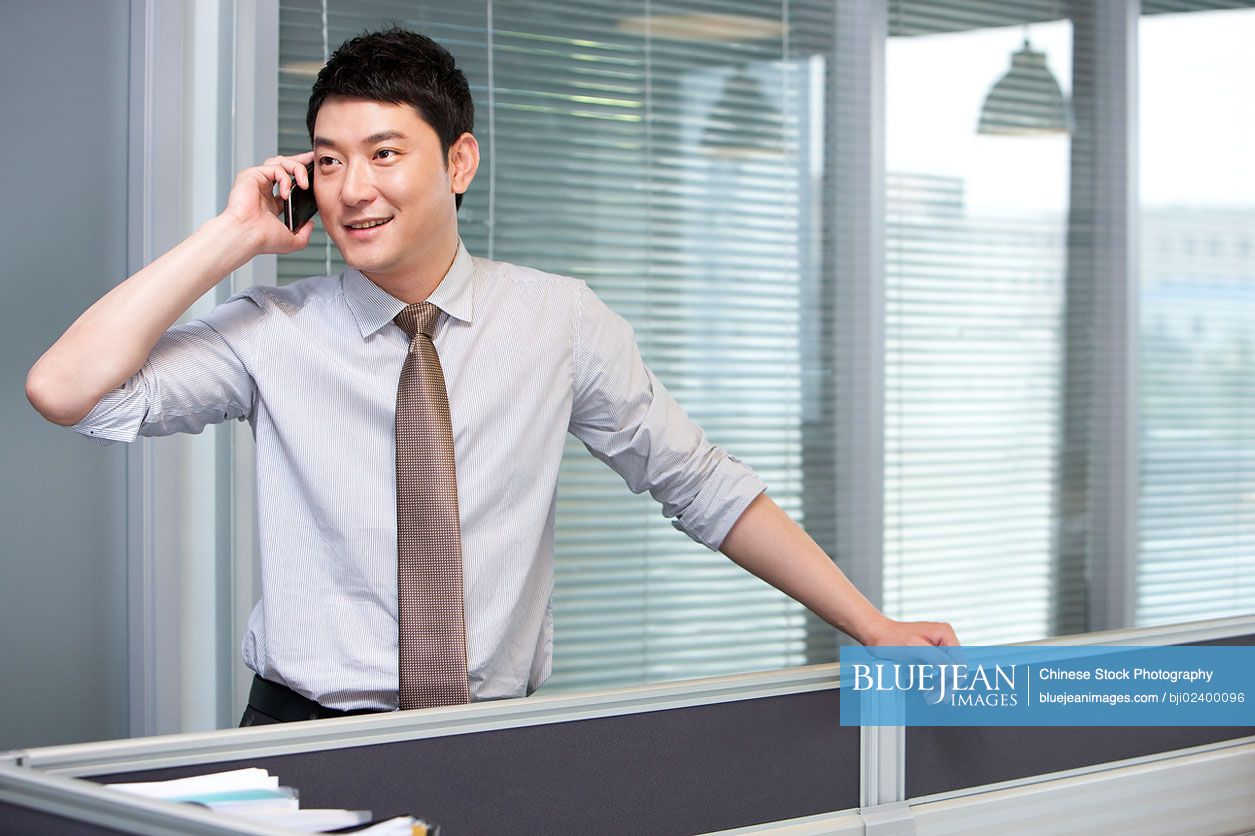 Confident Chinese businessman talking on cell phone