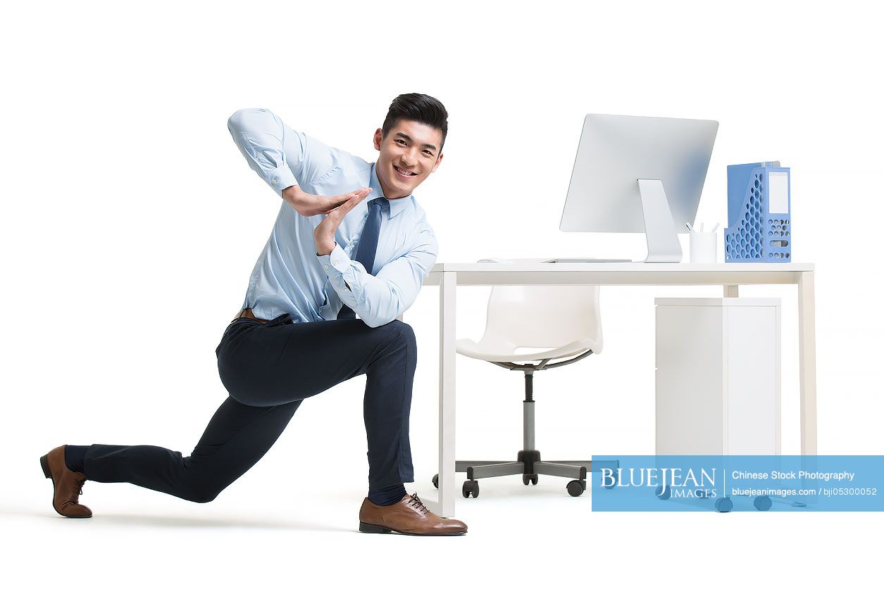 Young Chinese businessman exercising in office