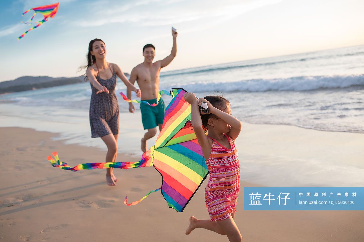 快乐的年轻家庭在沙滩放风筝