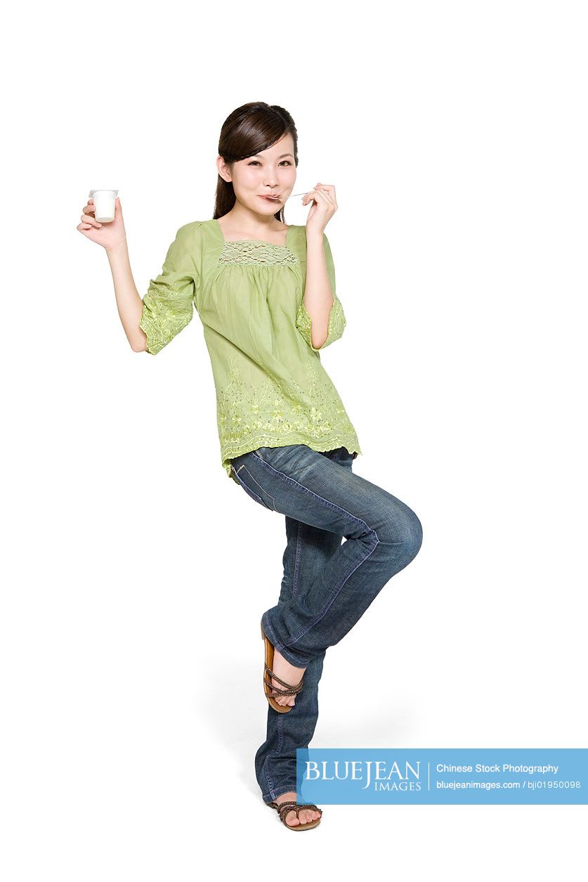 Portrait of young Chinese woman eating yogurt