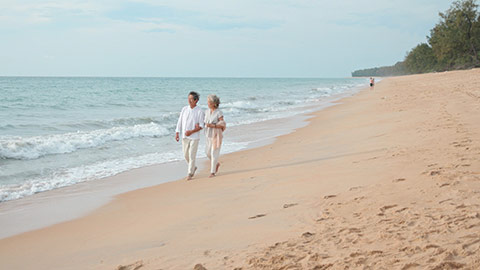 快乐老年夫妇在沙滩散步