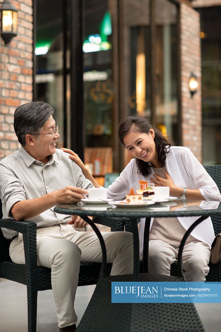 Mature Chinese couple having afternoon tea in coffee shop