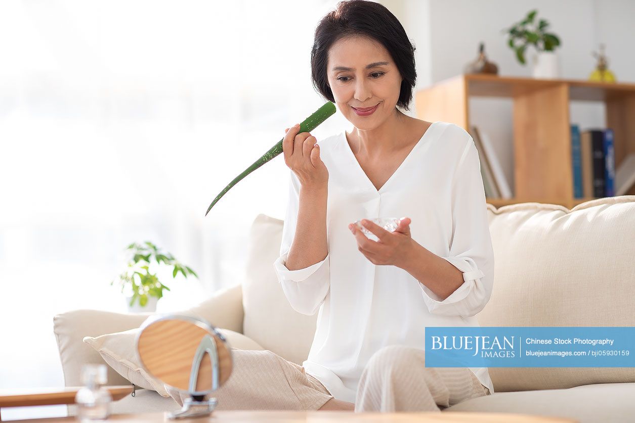 Mature Chinese woman applying aloe vera at home