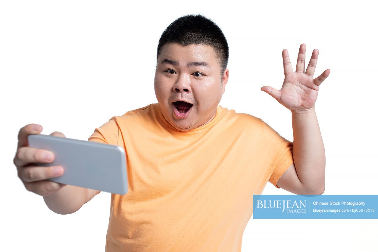 Young Chinese man taking selfie with smartphone