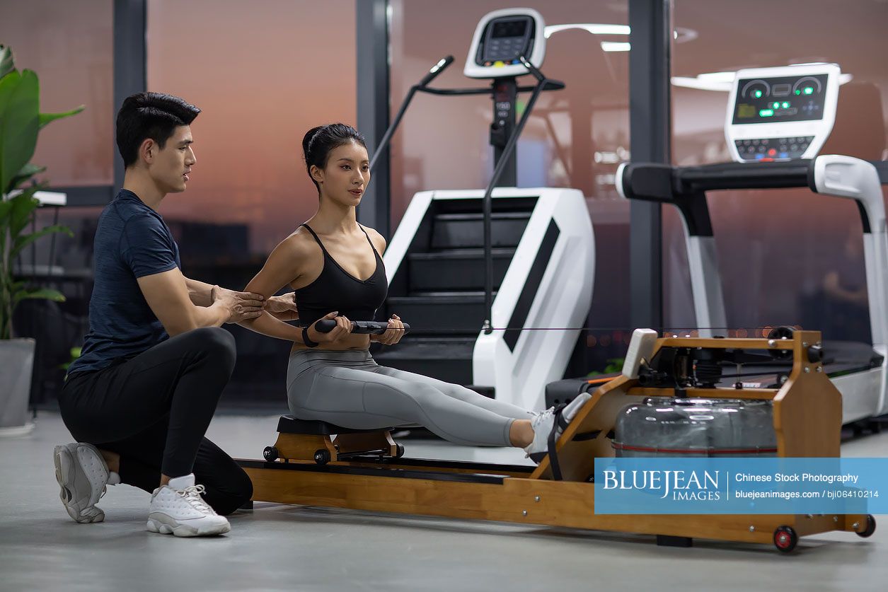 Young Chinese woman working out with personal trainer at gym
