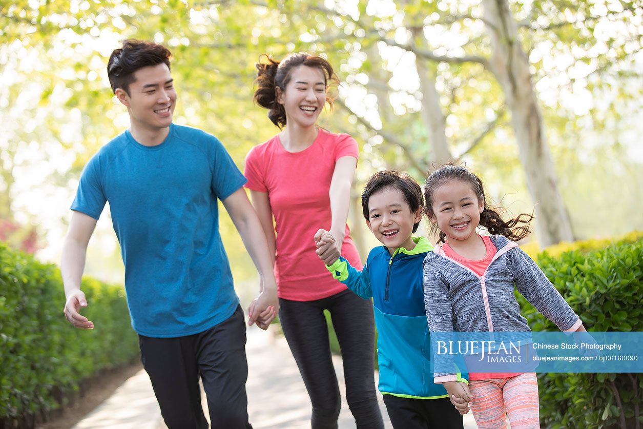 Happy young Chinese family playing in park