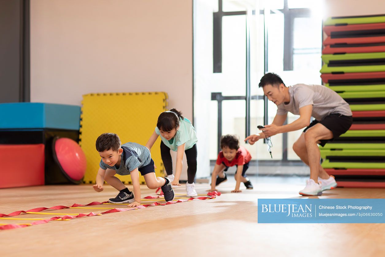 Cute Chinese children having exercise class in gym