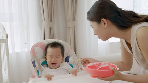 Young mom feeding her baby food