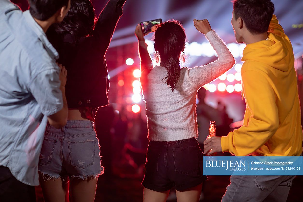 Happy young Chinese friends taking selfie at music festival