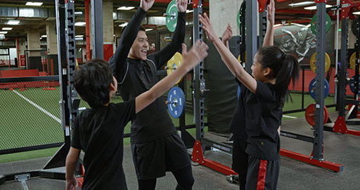 Cheerful Chinese children and coach high fiving in gym,4K