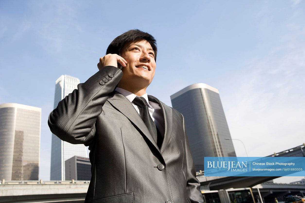 Chinese businessman on mobile phone, urban scene