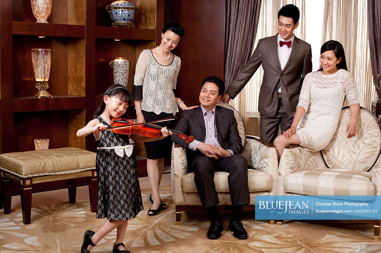 Little Chinese girl playing violin in front of family members