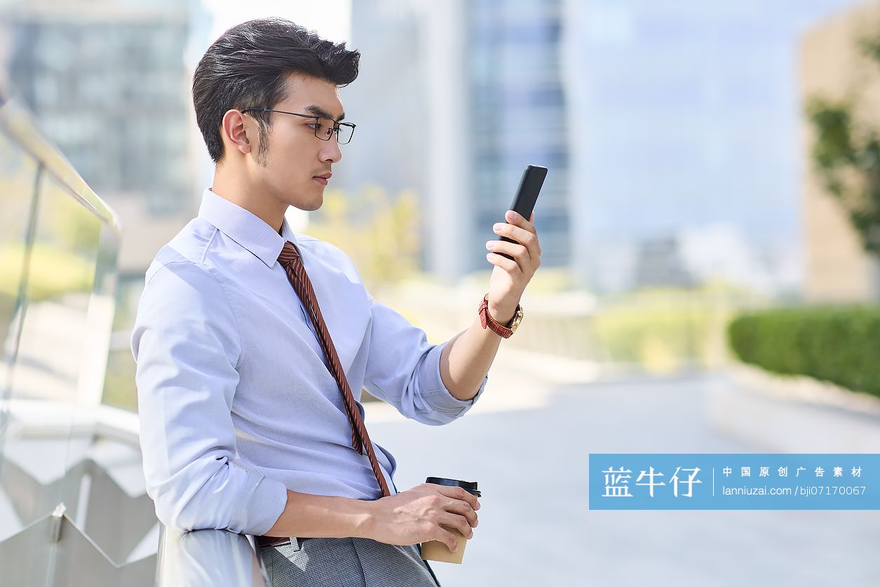 青年商务男士拿着咖啡和手机