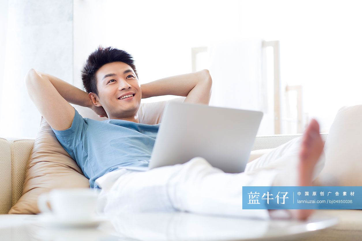 年轻男子在沙发上使用笔记本电脑
