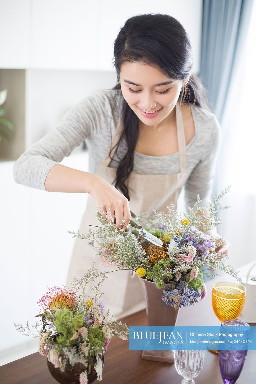 Young Chinese woman arranging flowers at home