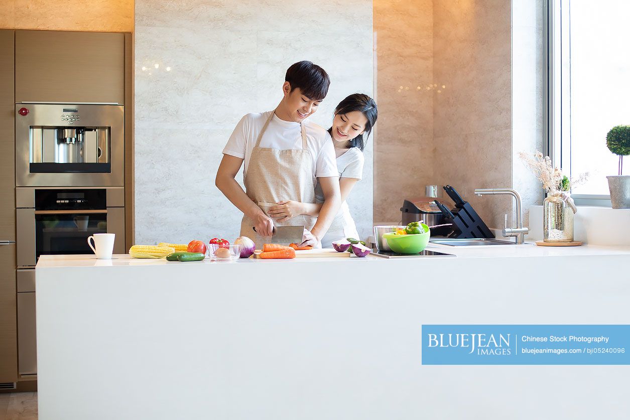 Happy young Chinese couple cooking in kitchen