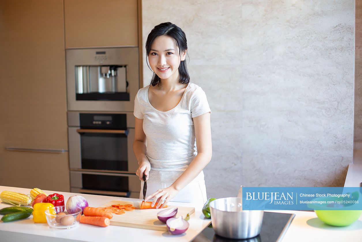 Young Chinese woman cooking in kitchen