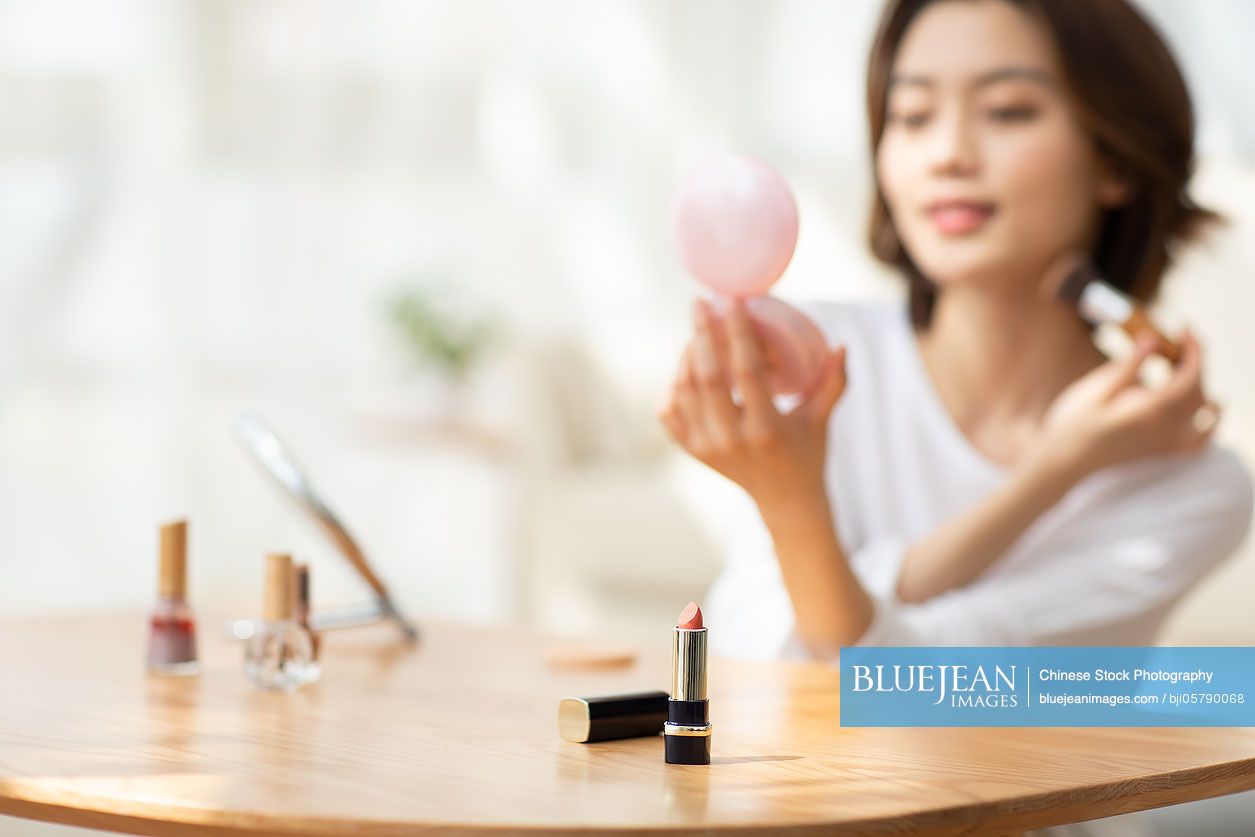 Young Chinese woman applying makeup at home