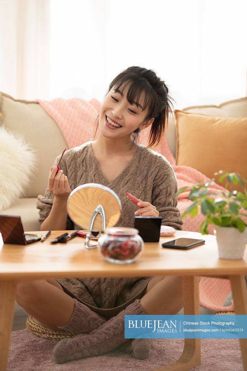 Young Chinese woman applying makeup at home