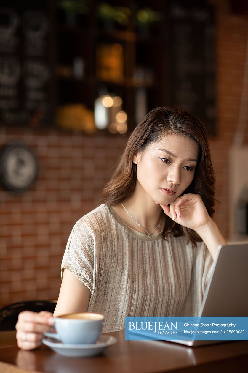 Elegant Chinese woman using laptop in cafe