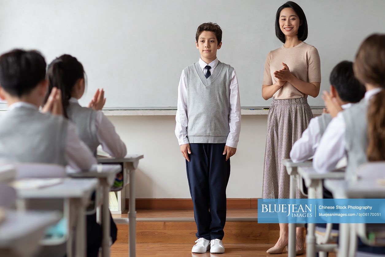 Young Chinese teacher introducing a new classmate in classroom