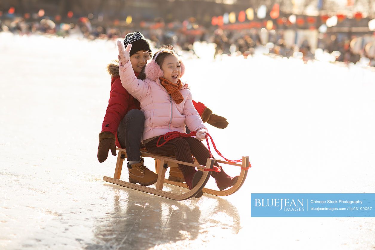 Happy Chinese sibling sledding outdoors