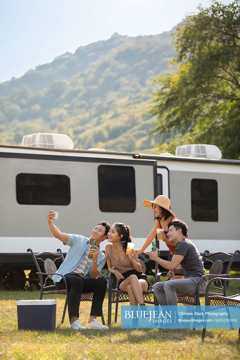 Happy young Chinese friends taking selfie outdoors
