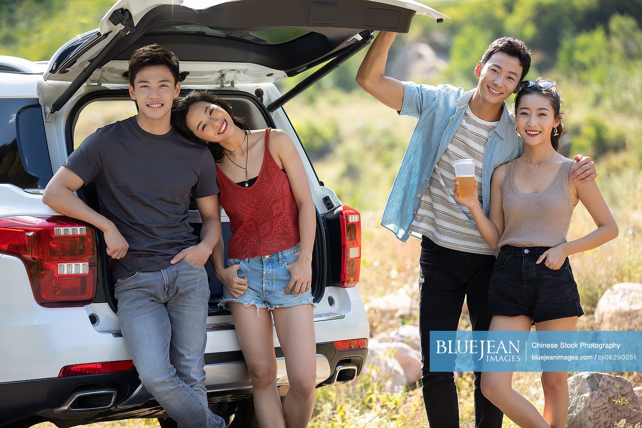 Happy young Chinese friends enjoying road trip