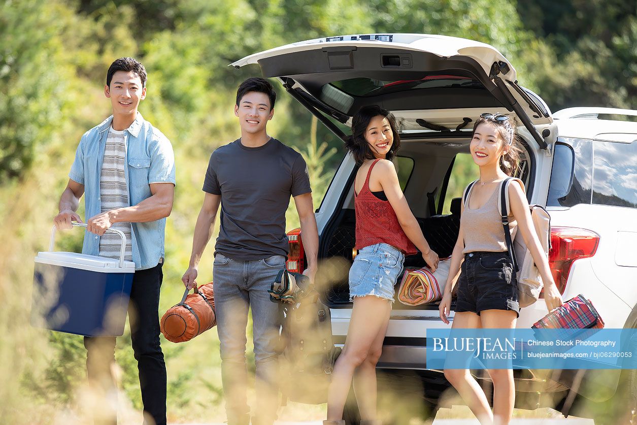 Happy young Chinese friends camping outdoors