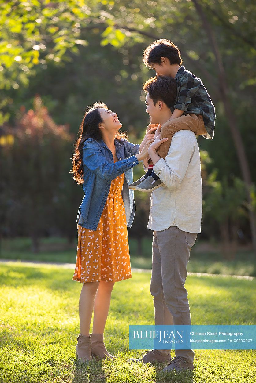 Happy young Chinese family having fun in park
