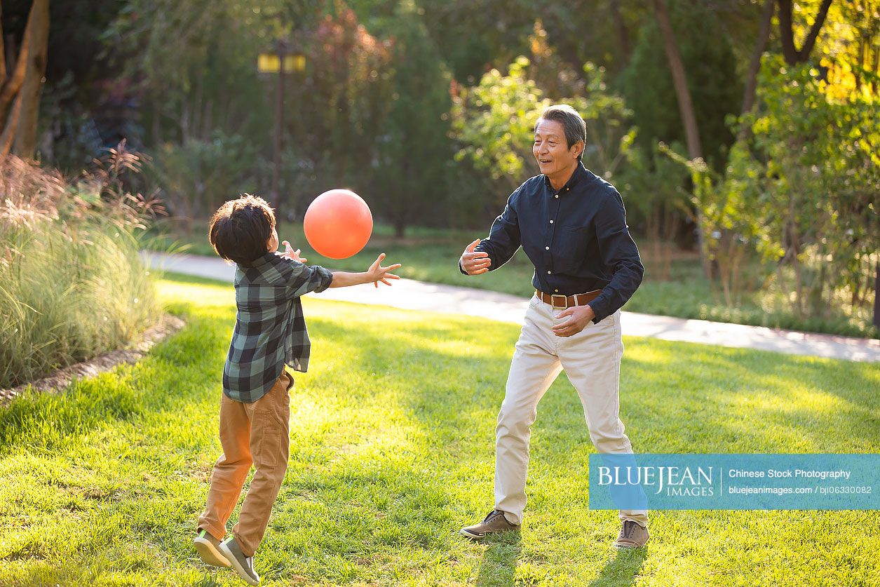 Happy Chinese grandfather and grandson having fun in park