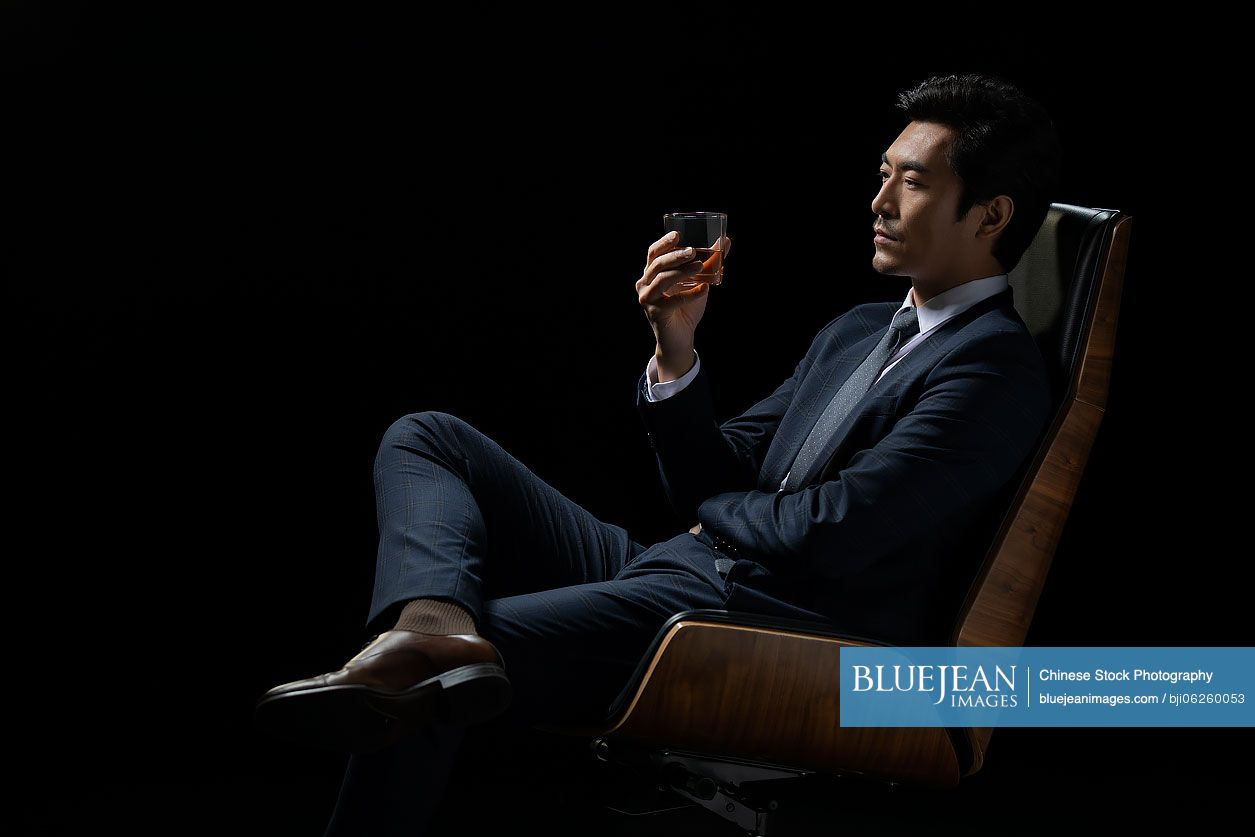 Successful Chinese businessman tasting whisky