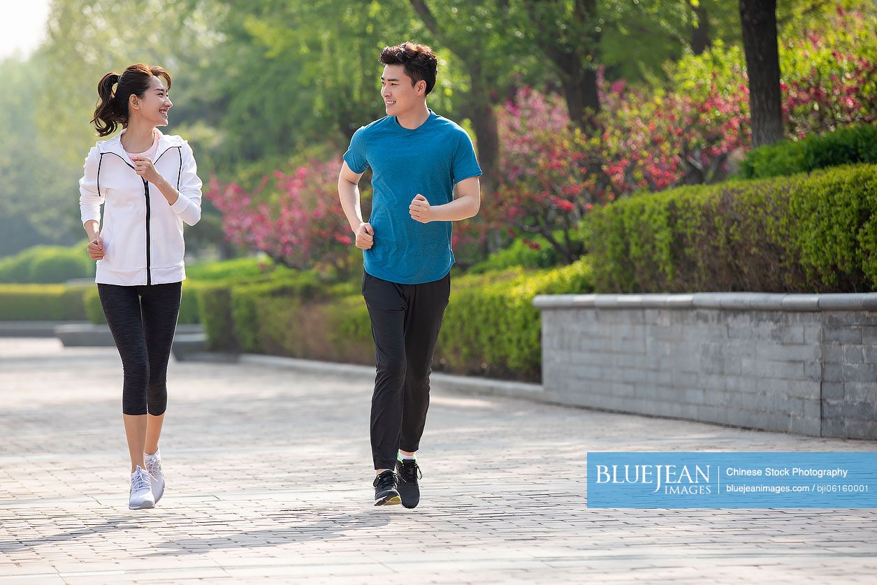 Happy young Chinese couple running in park