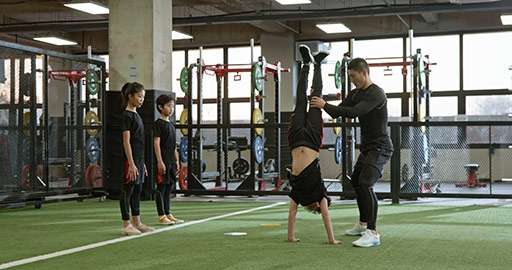 Active Chinese children having exercise class with their coach in gym,4K